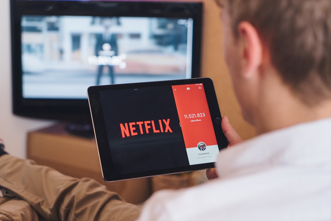 Netflix logo on a laptop screen showing various media icons like a movie reel, a controller, and a sports ball